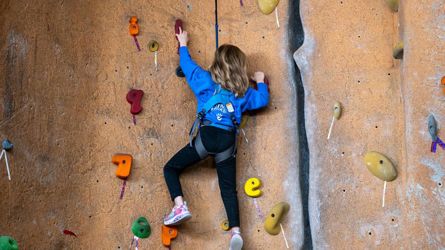 little girl climbing indoor rock climbing wall
