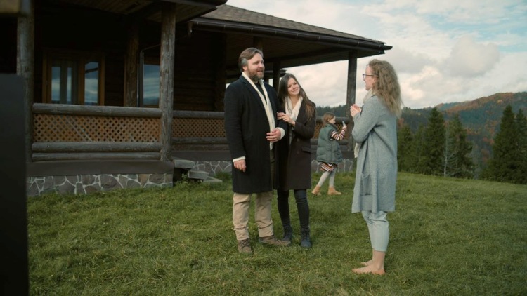 Family outside wooden house in grassy Colorado landscape