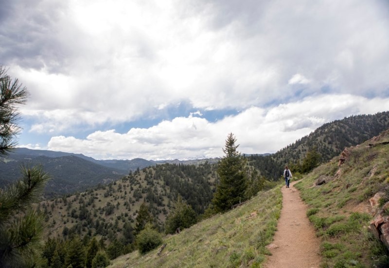 Hiker on dirt trail in scenic Colorado mountain landscape