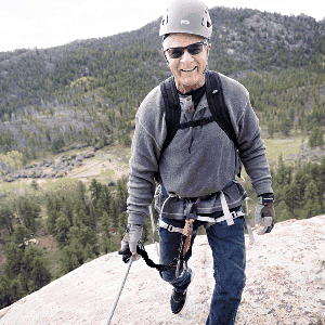 A man climbs rocks near Shoshana Ranch, wearing a helmet and harness for safety